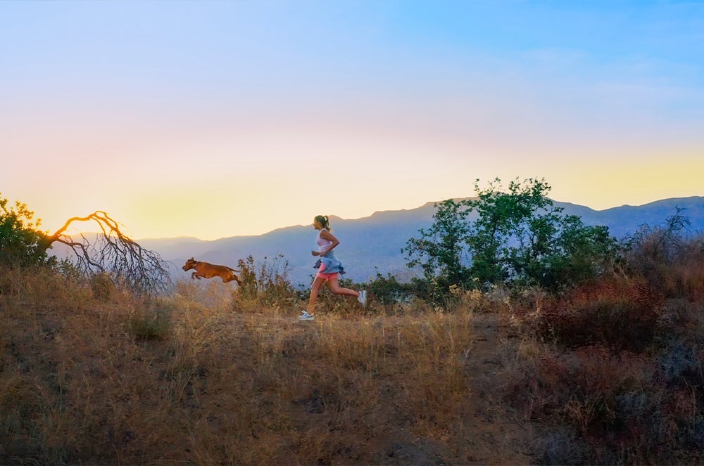 girl and dog running in mountains, wellness pet food